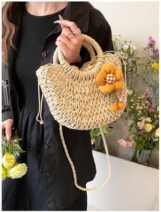 Dettaglio borsa in paglia intrecciata con ciondolo a fiore e fodera interna a coulisse