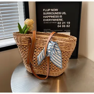 Detailed shot of woven straw tote bag with brown leather straps and striped silk scarf decoration