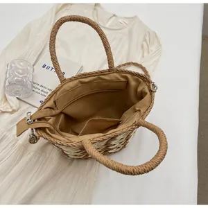 Detail view of woven straw tote with fabric lining, zipper closure, and internal pockets