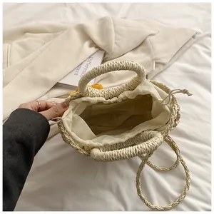 Dettaglio borsa in paglia intrecciata con chiusura a coulisse e fiori gialli