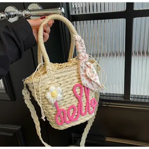 Detailed view of woven bucket bag with pink hello embroidery and floral scarf detail
