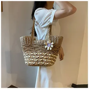 Detail of woven straw tote bag featuring intricate mesh patterns and floral pendant
