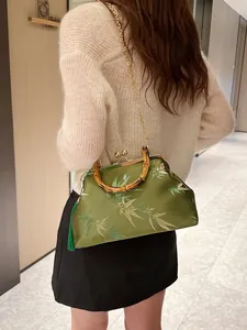 Olive green embroidered oriental handbag with bamboo handle shown on a model