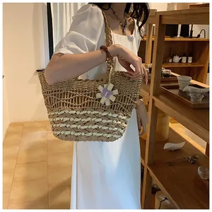 Detail of hand-woven straw tote with white wave patterns and purple floral charm