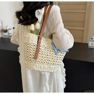 Detail of woven straw tote bag with brown leather straps and decorative blue striped scarf