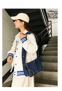 Detailaufnahme der blauen Denim-Umhängetasche mit Kontrastnähten auf einer Treppe