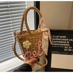 Macro detail of hand-woven straw bucket bag with floral scarf and hello lettering