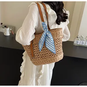 Detailed shot of large capacity hollow woven straw bag with blue striped silk scarf decoration