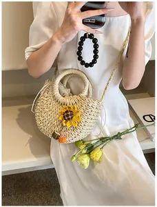 Dettaglio della borsa in paglia intrecciata con girasole e ciondoli a zucca arancio