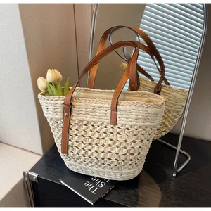 Close-up of woven straw tote bag featuring brown leather handles and hollow texture