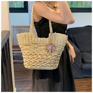 Close-up of woven straw tote bag featuring intricate diamond patterns and floral charm