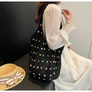 Detail of a black hollow-out crochet bag with colorful pearl embellishments and large capacity