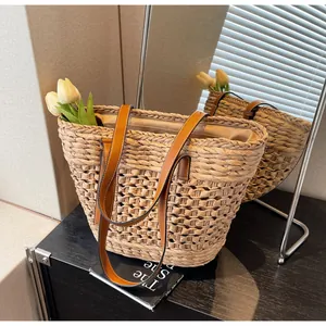 Detail view of woven straw tote bag with brown leather handles and white tulip flowers