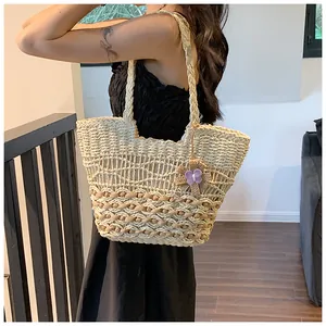 Detail of hand-woven hollow mesh texture on a beige straw shoulder bag with flower charm