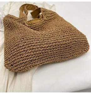 Detail shot of hollow-out woven texture and sturdy handles on tan straw beach bag