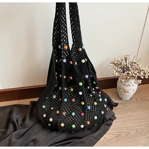 Detail of black crochet beach bag featuring colorful beads and hollow knit texture