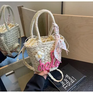 Detail of woven straw bucket bag with pink hello embroidery and floral scarf handle