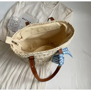 Top view of woven straw tote bag featuring brown leather handles and striped silk scarf bow