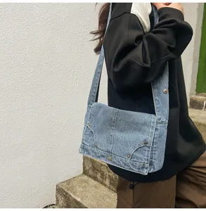 Detail der gewaschenen blauen Denim-Umhängetasche mit Nieten und modischem Taschendesign