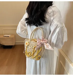 Detail of hand-woven beige straw bucket bag with floral scarf and hello embroidery