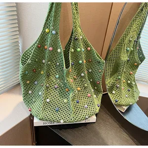 Detail of green knit beach tote with hollow crochet pattern and colorful pearl accents