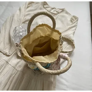 Detail shot of woven bucket bag featuring a drawstring liner and decorative floral scarf