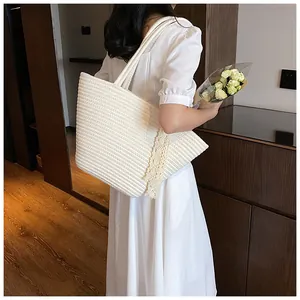 Detail of a cream-colored woven tote bag featuring delicate beige lace trim on the side