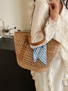 Handwoven straw tote bag with brown leather handles and a blue striped silk scarf detail