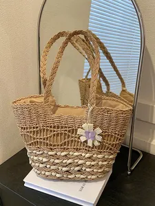 Handwoven straw tote bag for beach vacations featuring floral butterfly charms and lining