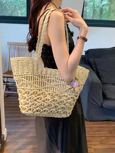 Straw woven tote bag with purple butterfly pendant shown on model for summer beach vacation