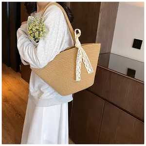 Detail of hand-woven khaki straw tote bag with white lace ribbon bow and large capacity