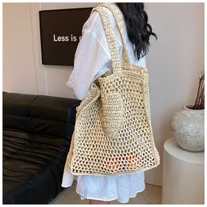 Detailed close-up of a hollow woven straw tote bag with shoulder straps and mini pouch
