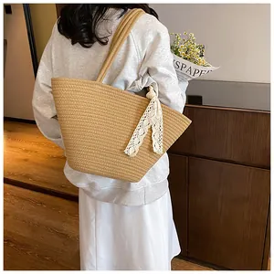Close-up of khaki woven tote bag featuring a white lace bow detail and rope handles