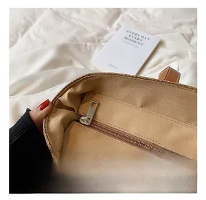 Detail view of the straw beach bag interior showing the metal zipper pocket and lining