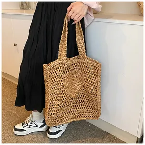 Detailed close-up of straw woven tote bag featuring a heart pattern and hollow knit craft