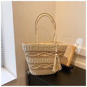 Detailaufnahme der beigen Strohtasche mit Wellenstruktur und Quasten-Anhänger