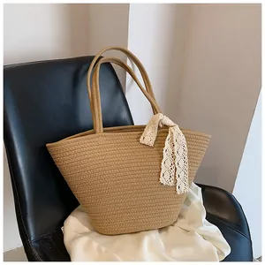 Close-up of khaki woven tote bag with straw texture and white lace bow detail