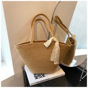 Detail of woven straw tote bag featuring decorative white crochet lace tie on the handle