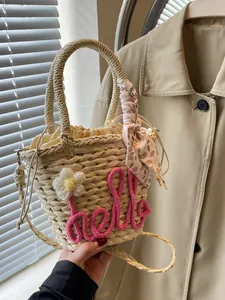 Woven straw handbag with pink hello embroidery and floral scarf on casual trench coat background