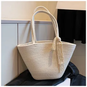 Detailed close-up of woven cream tote bag featuring elegant lace bow decoration