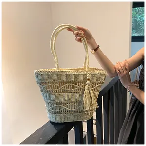 Detail der handgeflochtenen Strohtasche mit Wellenmuster und dekorativen Holzperlen-Quasten