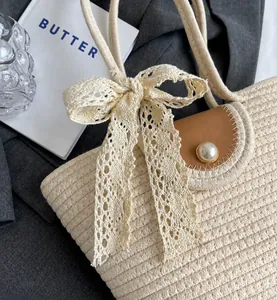 Détail du sac en paille beige avec nœud en dentelle, rabat en cuir et fermoir en perle