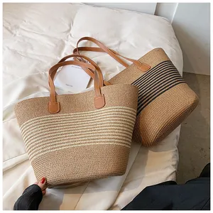Detail of woven straw tote bags with striped patterns and premium brown leather handles