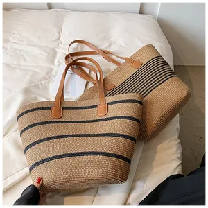 Detail of hand-woven straw tote bag with black stripes and brown leather handles