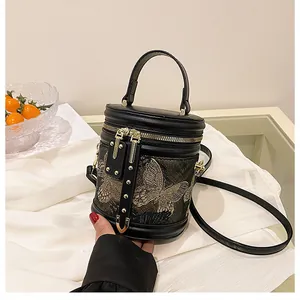 Detail of black bucket bag featuring butterfly embroidery and golden zipper closure