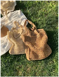 Close-up of hollow mesh straw tote bags in beige and khaki colors on green grass