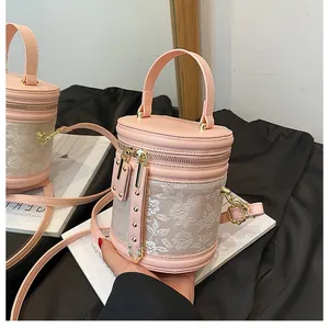 Detail of pink embroidered cylinder bag with floral patterns and gold hardware