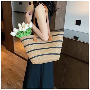 Detail of hand-woven straw tote with black stripes and brown faux leather handles