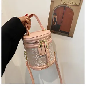 Detail of pink embroidered cylinder bucket bag with floral patterns and gold hardware