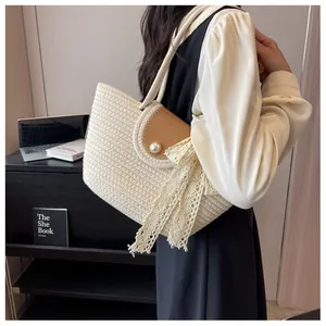Détail du cabas tissé avec rabat en cuir, fermoir perle et nœud en dentelle blanche